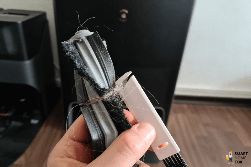 Mit Hilfe einer Reinigungsbürste werden Haare aus der Hauptbürste des Ecovacs Deebot X1 Omni entfernt